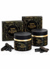Two black jars of Oudh Nabeel Black with gold detailing, accompanied by two matching black gift boxes and several loose dark brown oudh pods on a white background.
