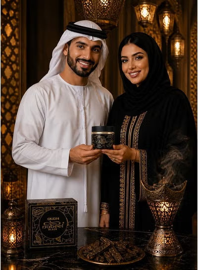 A man in a white kandura and sheath cap and a woman in a black abaya with gold embroidery hold a small black jar together. A branded product box reading 'Ole&Hana' and 'Al Mawlid' sits on a table with decorative lanterns and a incense burner in a warm, ornate interior.